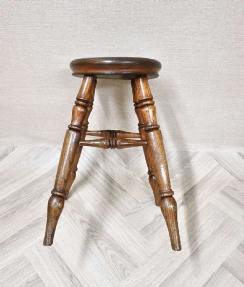 A nineteenth-century turned wooden Windsor stool featuring a circular polished seat supported by four splayed turned legs and turned stretchers. View III