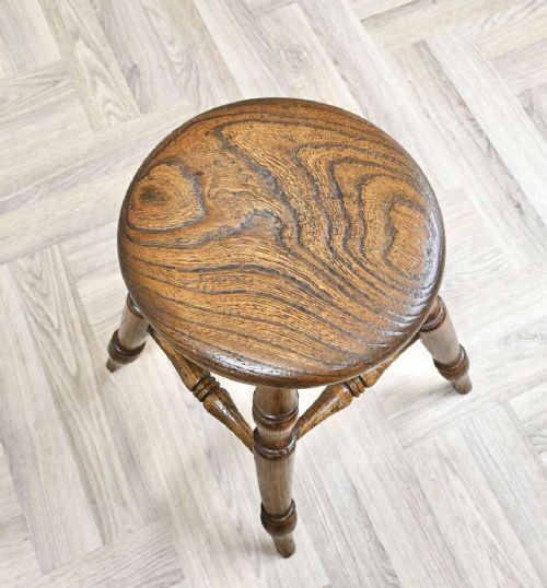 A nineteenth-century turned wooden Windsor stool featuring a circular polished seat supported by four splayed turned legs and turned stretchers. View IV