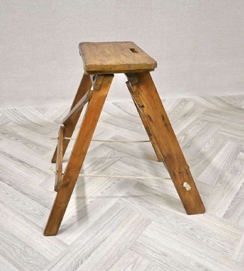A short folding pine step ladder with three treads, a flat top step, and a rope support brace. View III