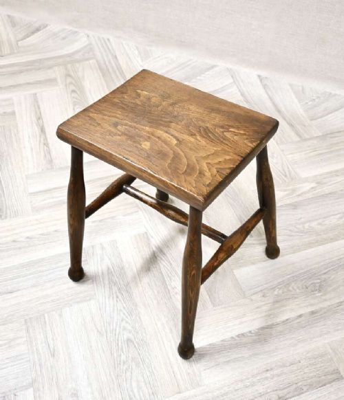 A small rectangular dark timber antique dairy stool featuring four turned legs joined by cross stretchers. View II