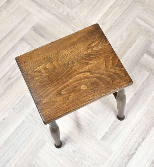 A small rectangular dark timber antique dairy stool featuring four turned legs joined by cross stretchers. View III