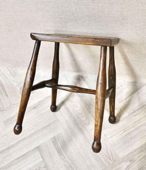 A small rectangular dark timber antique dairy stool featuring four turned legs joined by cross stretchers. View IV