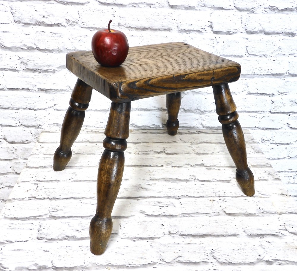 A low dark wooden hearth stool featuring a thick rectangular seat supported by four turned splayed legs. View II