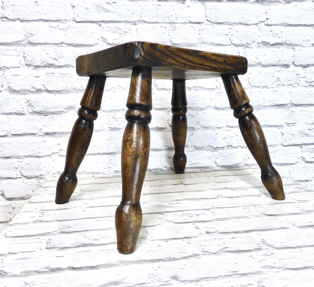 A low dark wooden hearth stool featuring a thick rectangular seat supported by four turned splayed legs. View IV