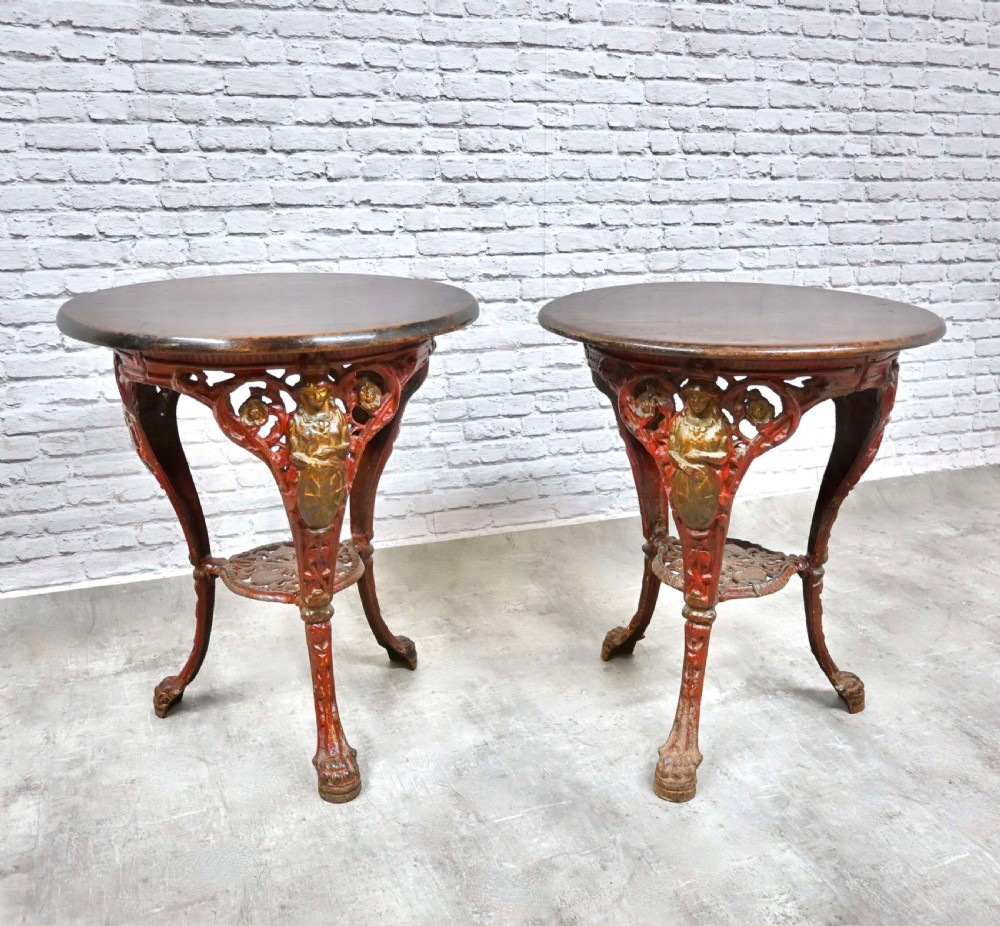 A pair of circular pub tables featuring dark wooden tops supported by painted red and gold cast iron tripod bases with Britannia relief figures. View VIII