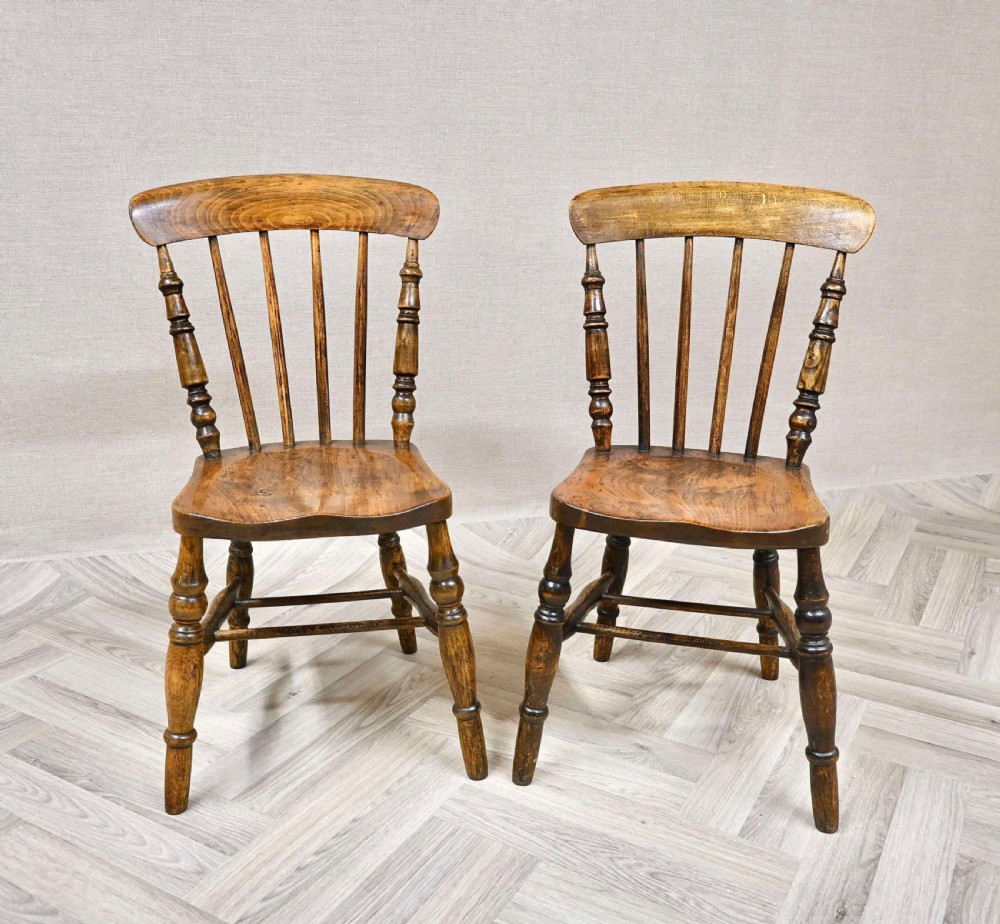 A pair of antique brown wooden Windsor dining chairs with turned legs and spindle backrests. View II