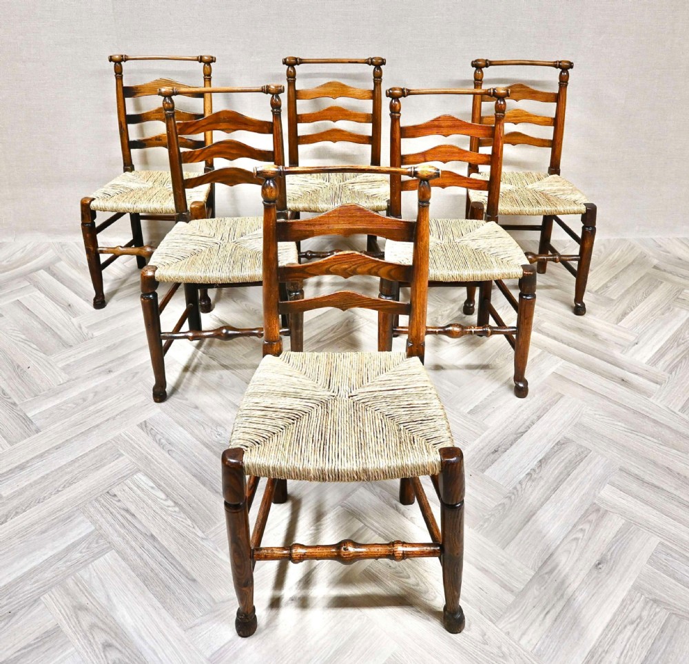 A set of six dark wood ladderback dining chairs with hand-woven rush seats arranged on a grey herringbone floor. View II