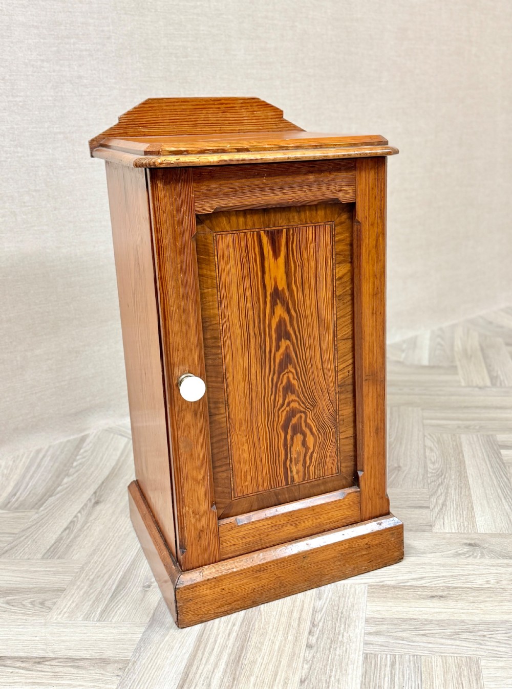 An antique pine pot cupboard featuring a single panelled door with a white ceramic knob, set on a solid plinth base. View II