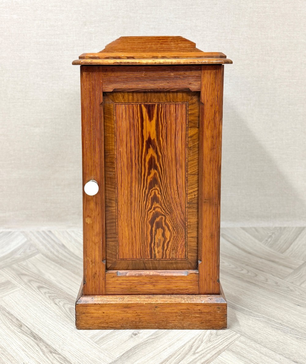 An antique pine pot cupboard featuring a single panelled door with a white ceramic knob, set on a solid plinth base. View VI