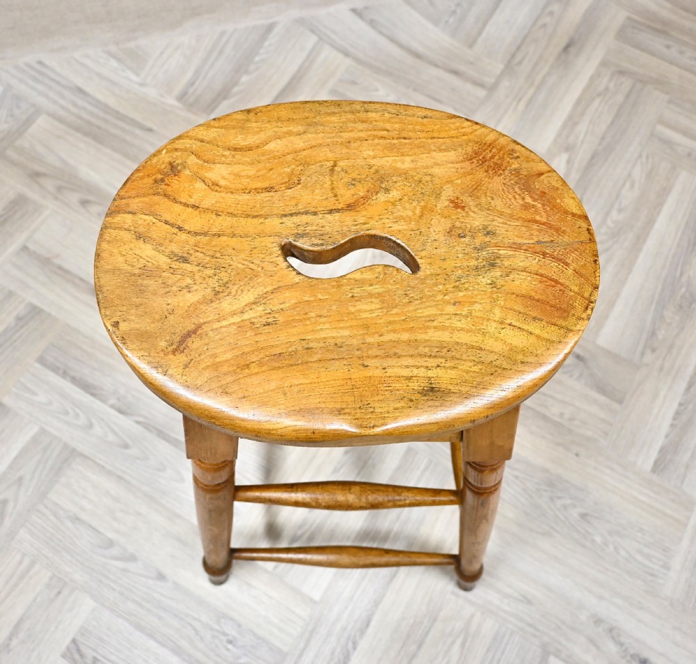 A tall 19th-century wooden bar stool featuring turned legs, lower footrest stretchers, and a rounded seat with a carved handhold slot. View III