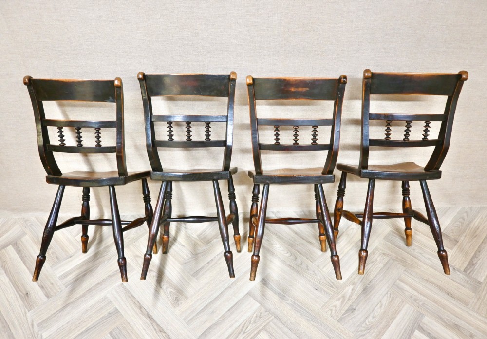 A set of four 19th-century wooden Windsor kitchen dining chairs featuring shaped elm seats, bar backs with spindle details, turned legs, and H-stretchers. View III