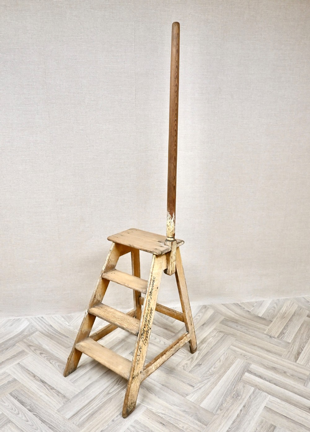 Light pine wooden step ladder featuring an extended vertical handrail pole and hand-painted black lettering along the side frame.