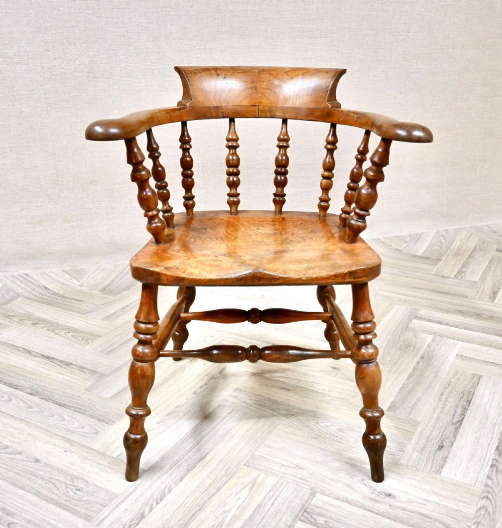 A Victorian Windsor smokers bow armchair in warm brown timber featuring turned spindles and a shaped saddle seat.