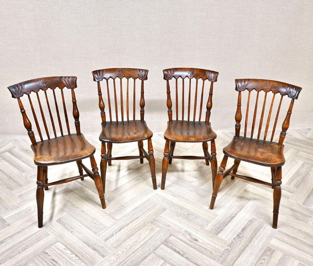 A set of four dark brown wooden Eastlake Windsor dining chairs featuring carved crest rails, spindle backs, contoured solid seats, and turned legs. View VI