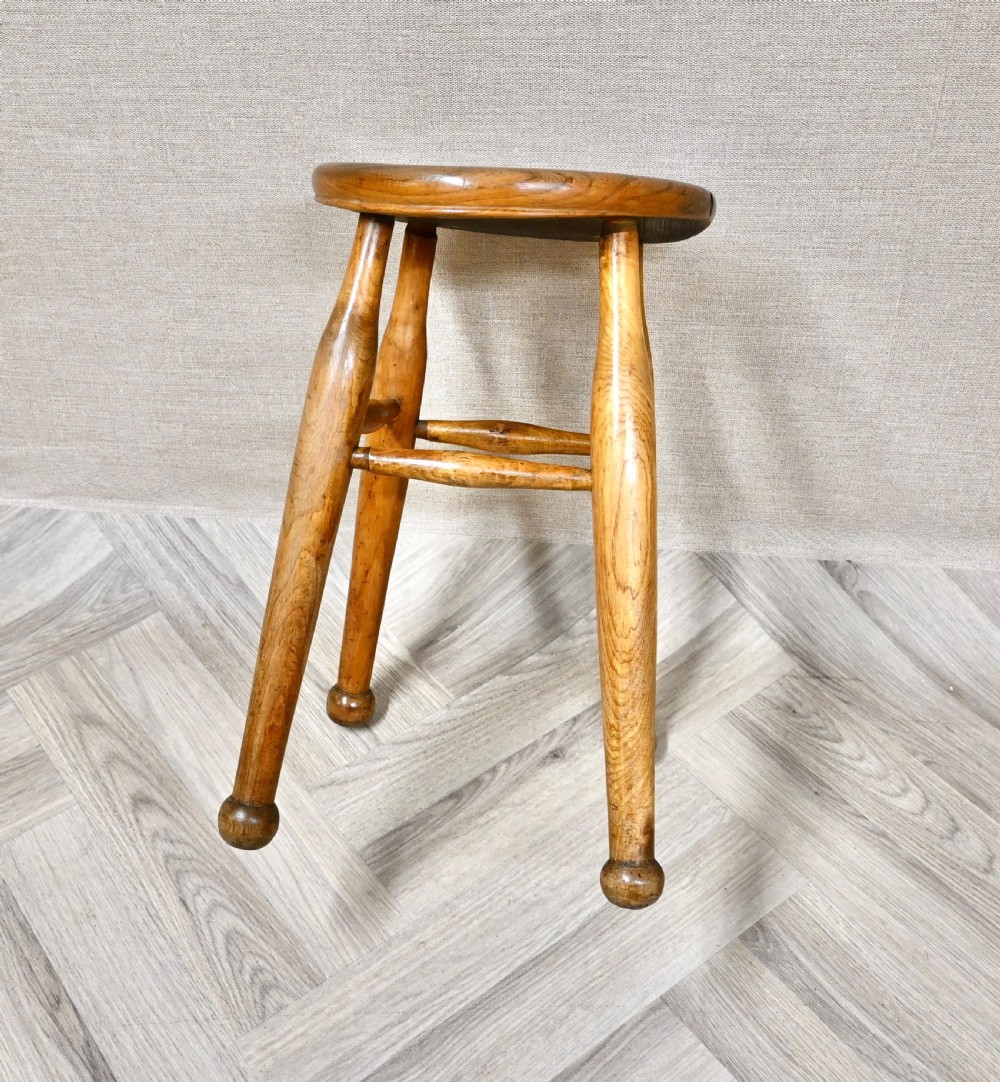 A 19th-century rustic wooden stool featuring a contoured round seat, splayed turned legs ending in ball feet, and turned stretchers. View IV