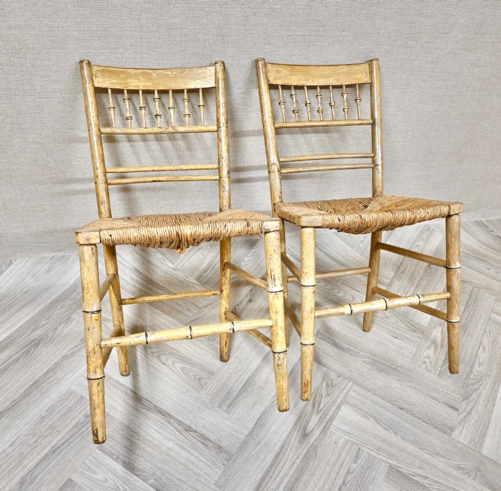 A pair of antique painted bamboo side chairs featuring turned spindle backrests and woven rush seats. View III