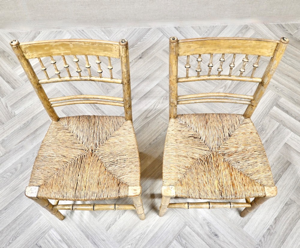 A pair of antique painted bamboo side chairs featuring turned spindle backrests and woven rush seats. View IV