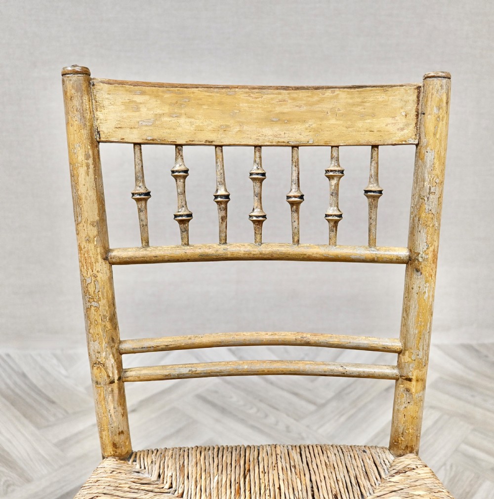 A pair of antique painted bamboo side chairs featuring turned spindle backrests and woven rush seats. View V