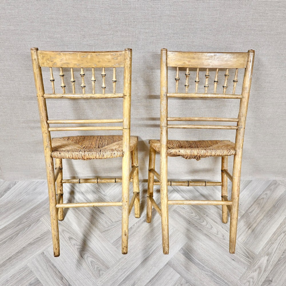 A pair of antique painted bamboo side chairs featuring turned spindle backrests and woven rush seats. View VI