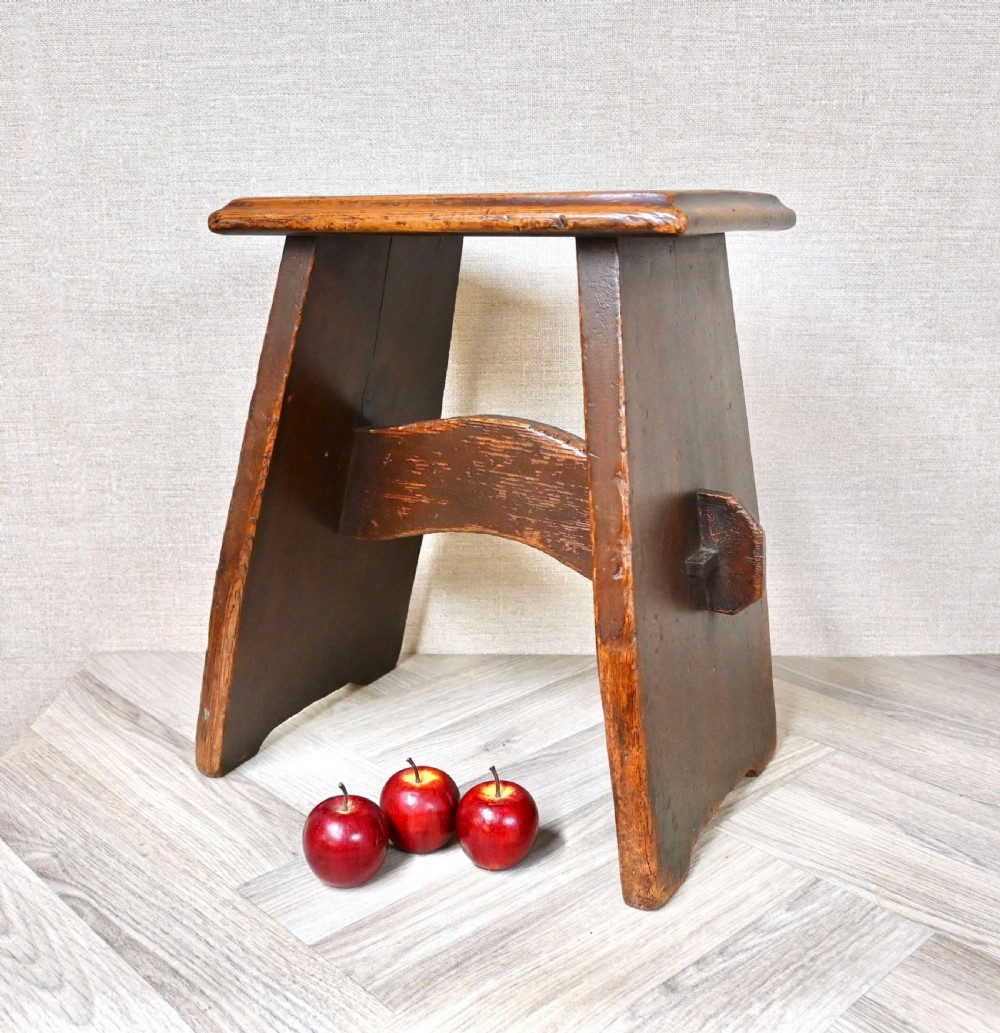 A 19th-century dark oak stool featuring a rectangular top seat supported by slanted slab legs and a through-tenon stretcher secured with a wooden wedge. View III
