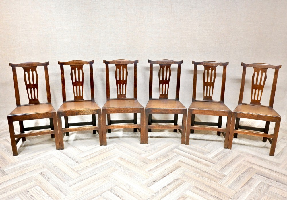 A set of six Georgian oak country dining chairs featuring pierced back splats, flat wooden seats, and sturdy stretchered legs. View II