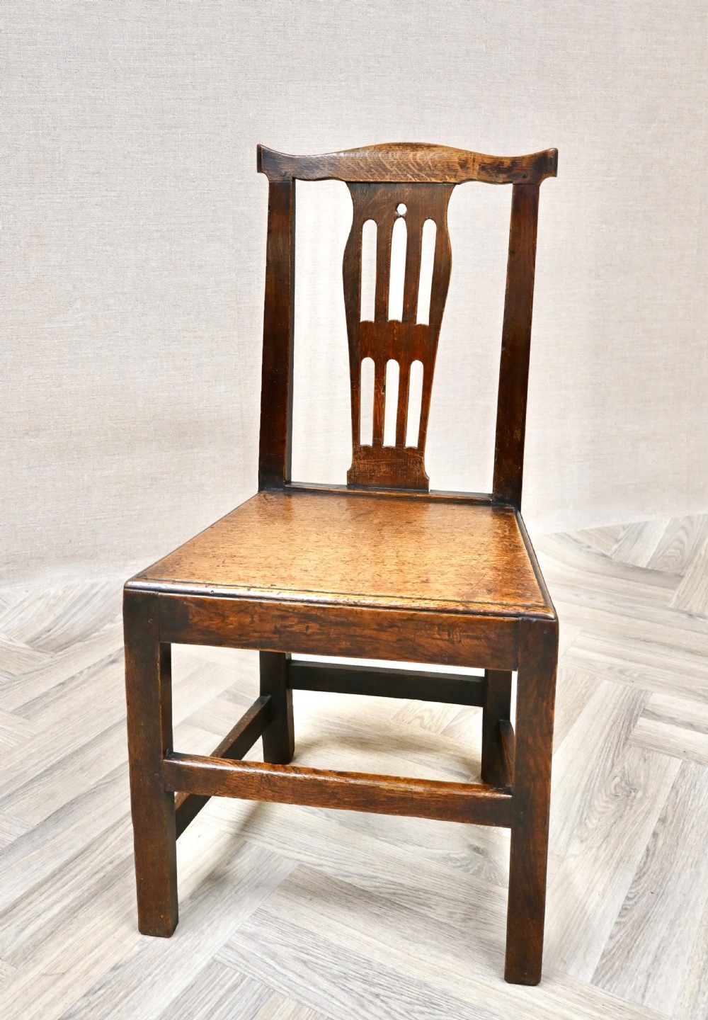 A set of six Georgian oak country dining chairs featuring pierced back splats, flat wooden seats, and sturdy stretchered legs. View V