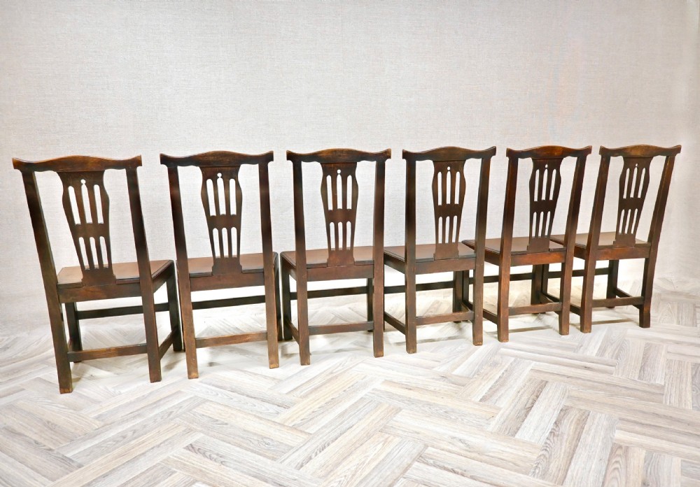 A set of six Georgian oak country dining chairs featuring pierced back splats, flat wooden seats, and sturdy stretchered legs. View VI