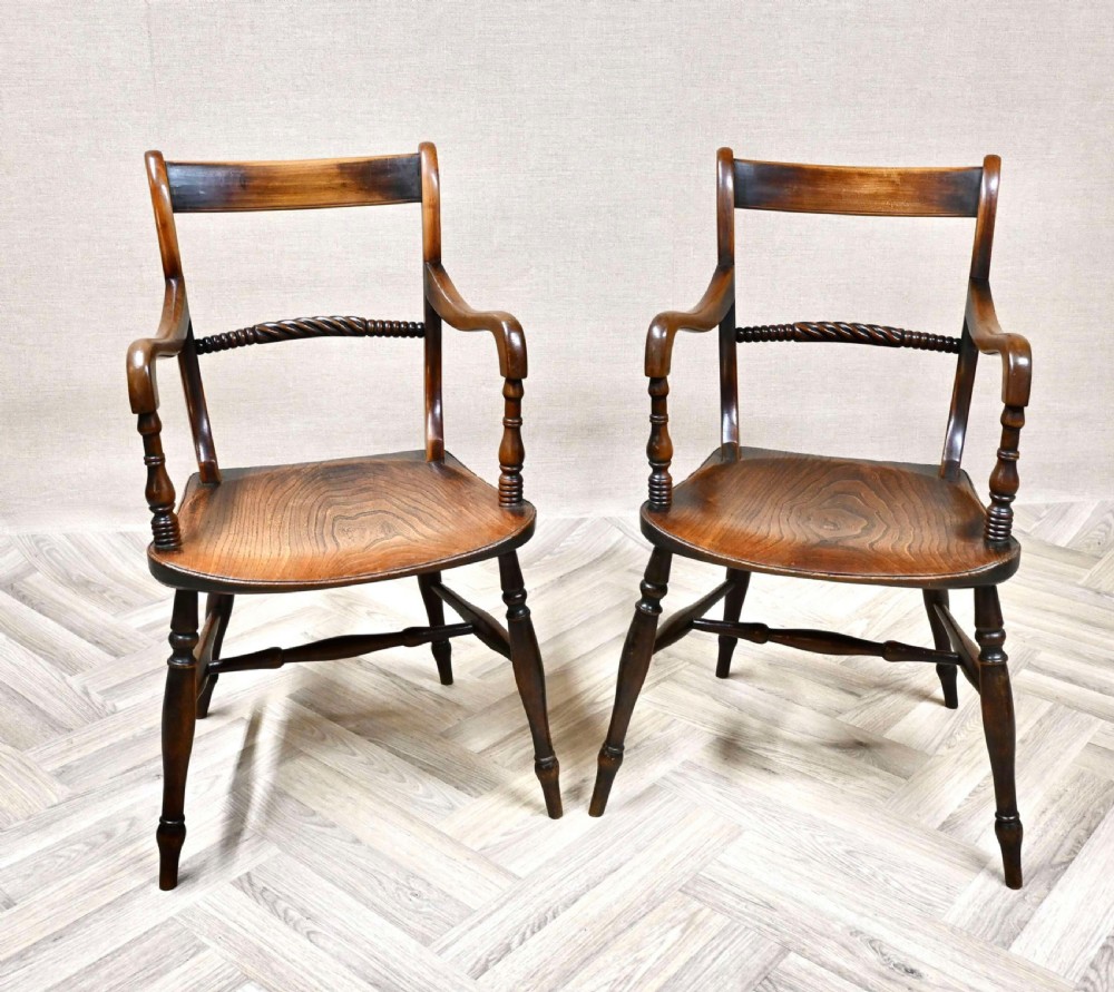 A pair of antique wooden Windsor barback armchairs featuring horizontal ropetwist back rails, shaped solid seats, swept armrests, and turned legs.