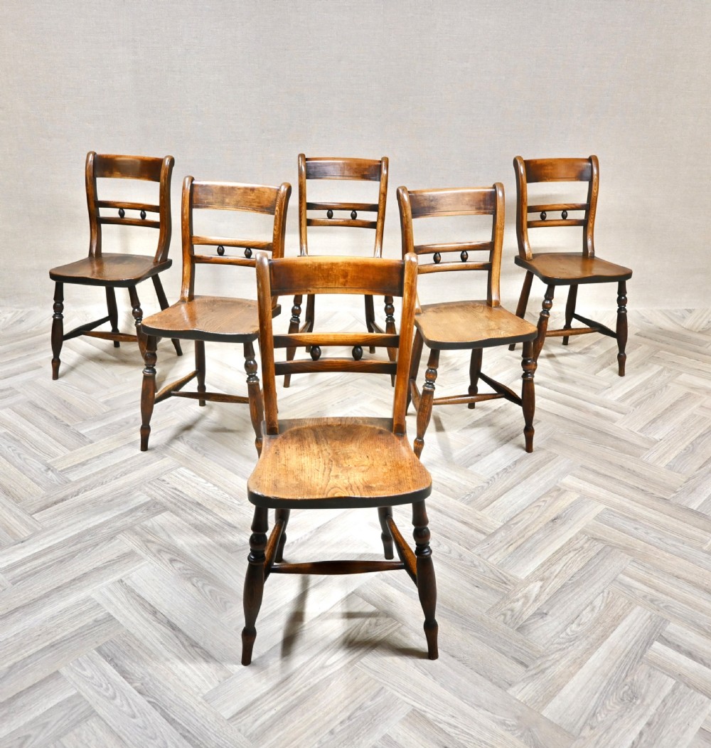 A set of six matching antique wooden Windsor barback dining chairs featuring turned legs, horizontal back rails with central bobbin detail, and contoured wooden seats.