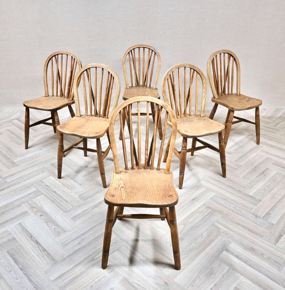 A set of six light timber Windsor kitchen chairs featuring hoop backs with vertical stick spindles and turned legs.