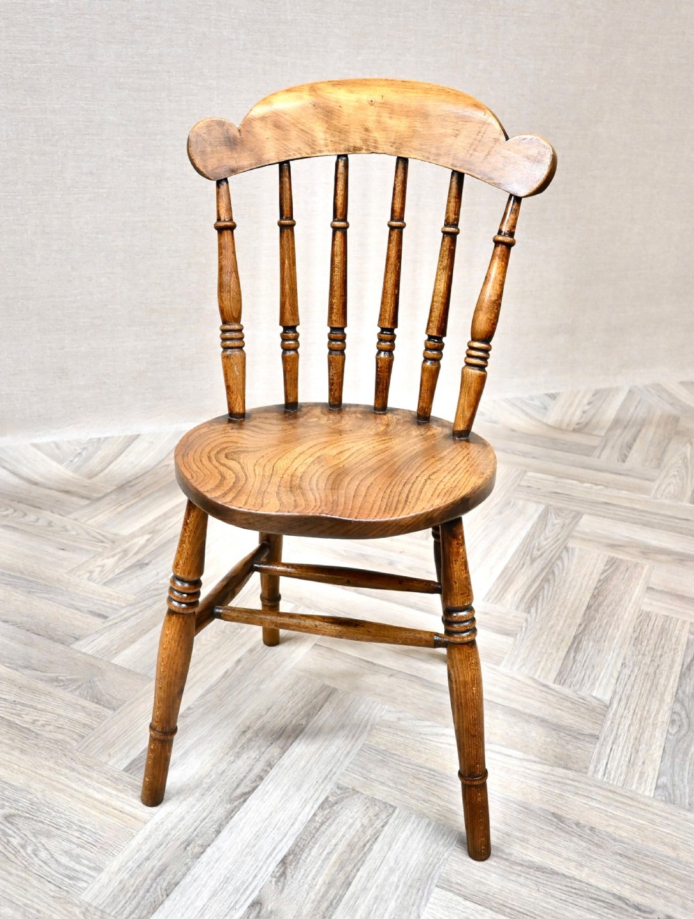 A set of eight wooden Windsor dining chairs featuring shaped cresting top rails, spindle backs, circular penny seats, and turned legs with stretchers. View VI
