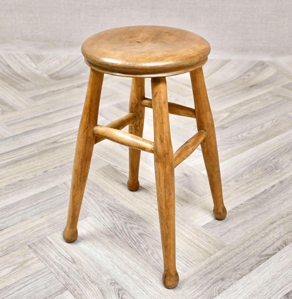 A nineteenth-century round wooden stool featuring four splayed turned legs supported by round stretchers.