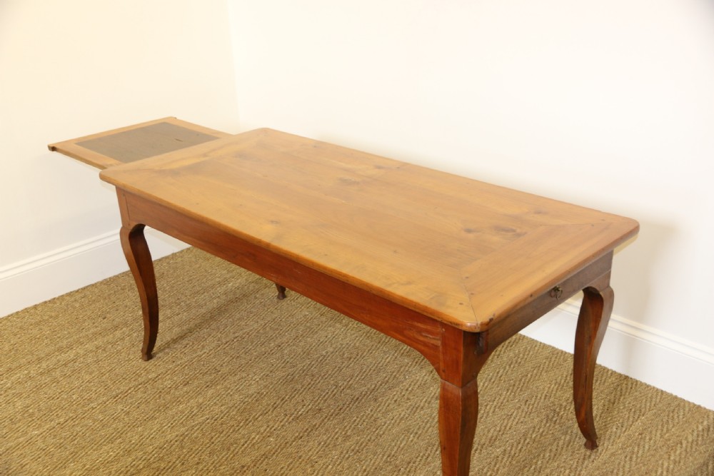 An antique French cherrywood farmhouse dining table featuring slender cabriole legs, an end drawer, and an extending pull-out slide. View V