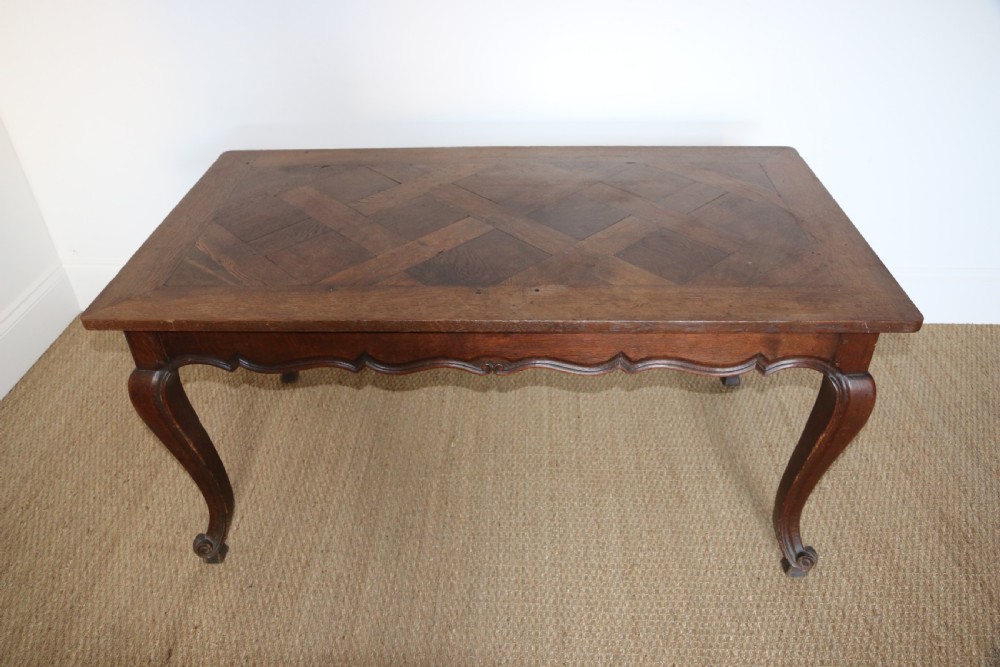 A rectangular dark oak table featuring an inlaid parquet pattern top, a scalloped apron, and sweeping cabriole legs with scroll feet.