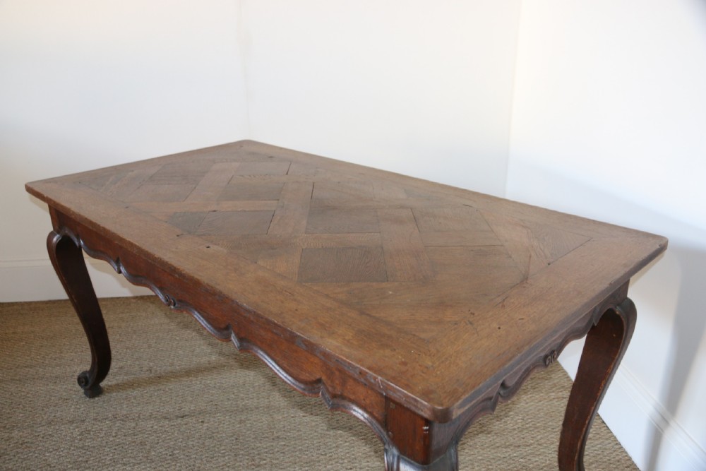 A rectangular dark oak table featuring an inlaid parquet pattern top, a scalloped apron, and sweeping cabriole legs with scroll feet. View IV