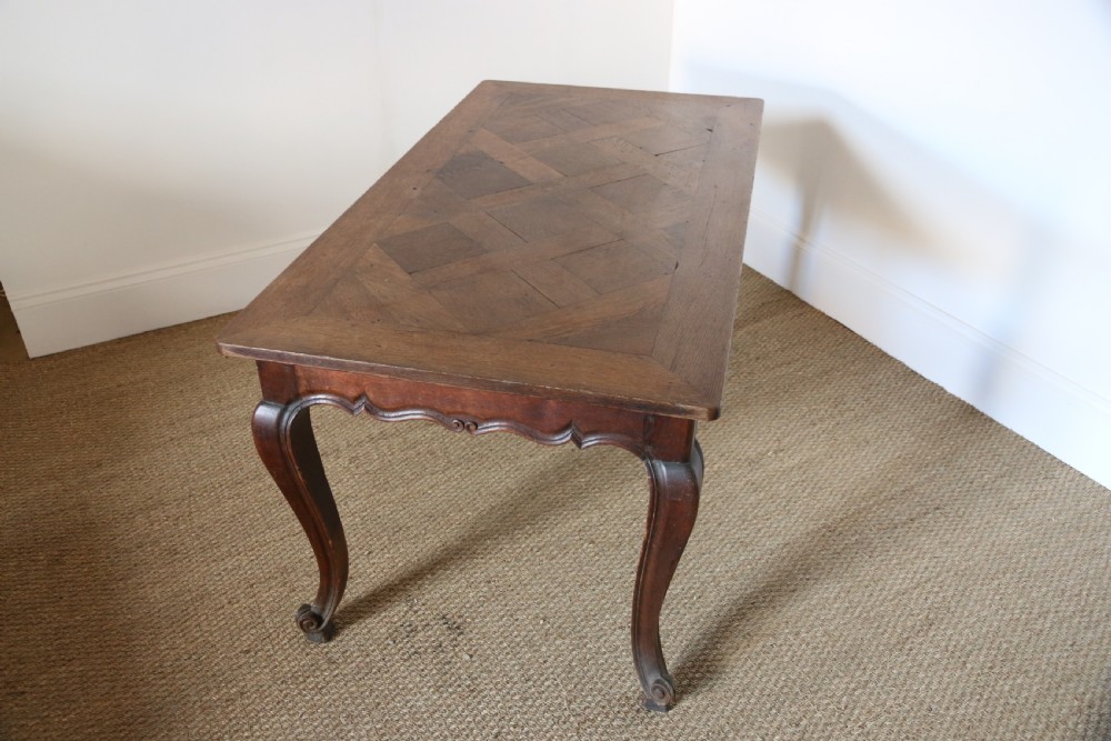 A rectangular dark oak table featuring an inlaid parquet pattern top, a scalloped apron, and sweeping cabriole legs with scroll feet. View VIII