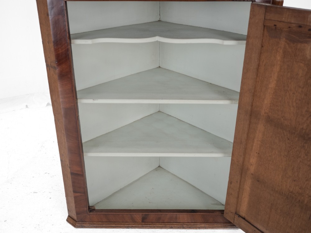 A late 18th-century Georgian oak wall-hanging corner cupboard featuring mahogany crossbanding, an inlaid central lozenge motif, a moulded top cornice, and brass H-hinges. View VIII