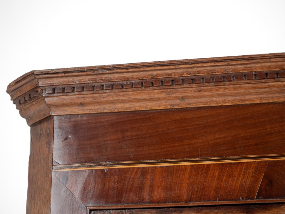 A late 18th-century Georgian oak wall-hanging corner cupboard featuring mahogany crossbanding, an inlaid central lozenge motif, a moulded top cornice, and brass H-hinges. View XIII