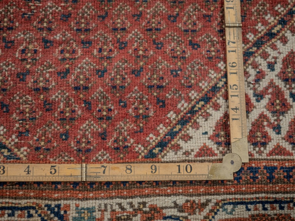 A rectangular late 19th-century handwoven Persian Mir Seraband rug featuring a repeating boteh pattern in terracotta red, blue, and cream. View X