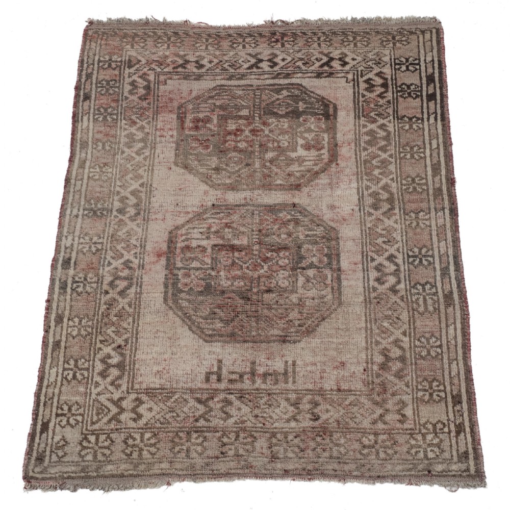 A small rectangular hand-knotted wool rug featuring two central octagonal gul medallions on a faded pink and beige ground with geometric borders.