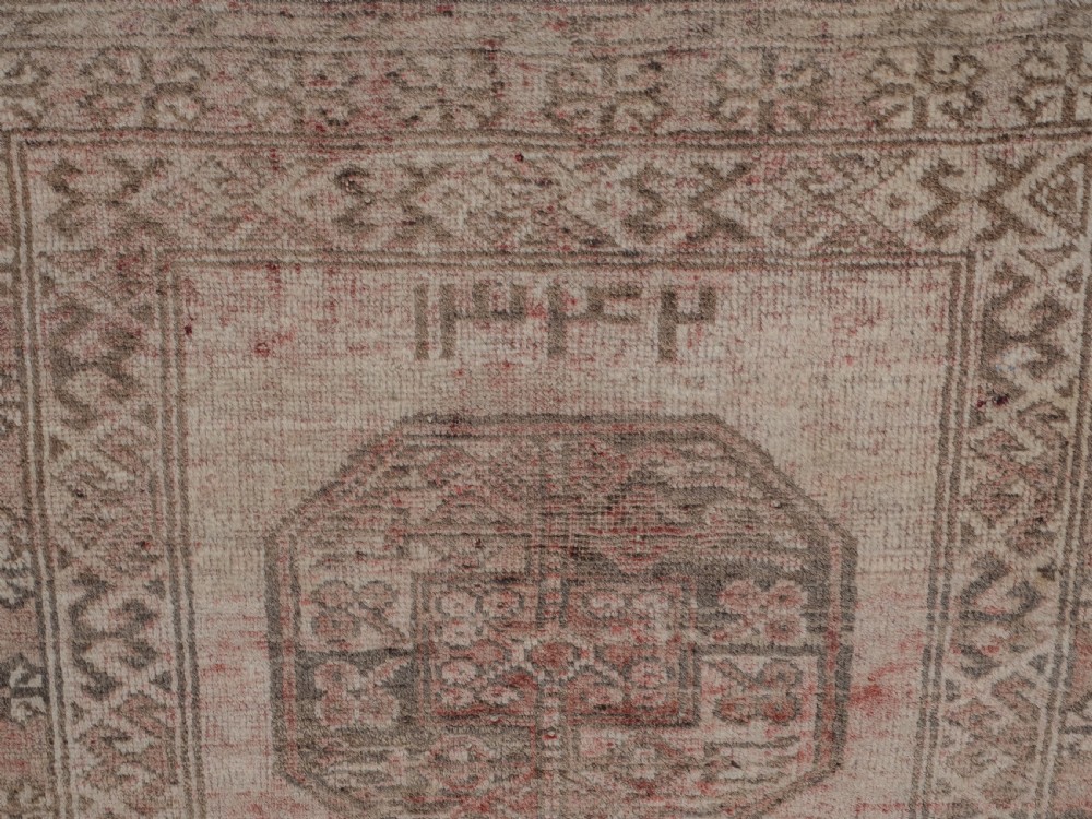 A small rectangular hand-knotted wool rug featuring two central octagonal gul medallions on a faded pink and beige ground with geometric borders. View II