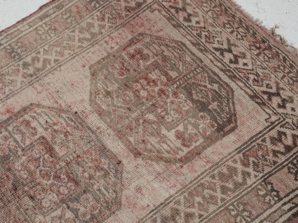 A small rectangular hand-knotted wool rug featuring two central octagonal gul medallions on a faded pink and beige ground with geometric borders. View VI