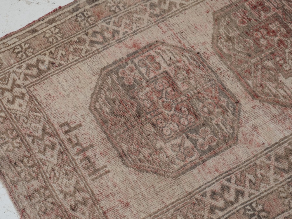 A small rectangular hand-knotted wool rug featuring two central octagonal gul medallions on a faded pink and beige ground with geometric borders. View VII