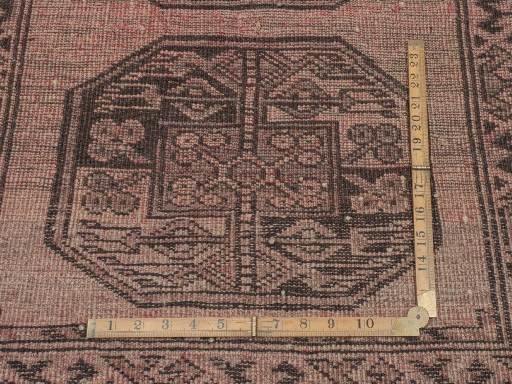 A small rectangular hand-knotted wool rug featuring two central octagonal gul medallions on a faded pink and beige ground with geometric borders. View IX
