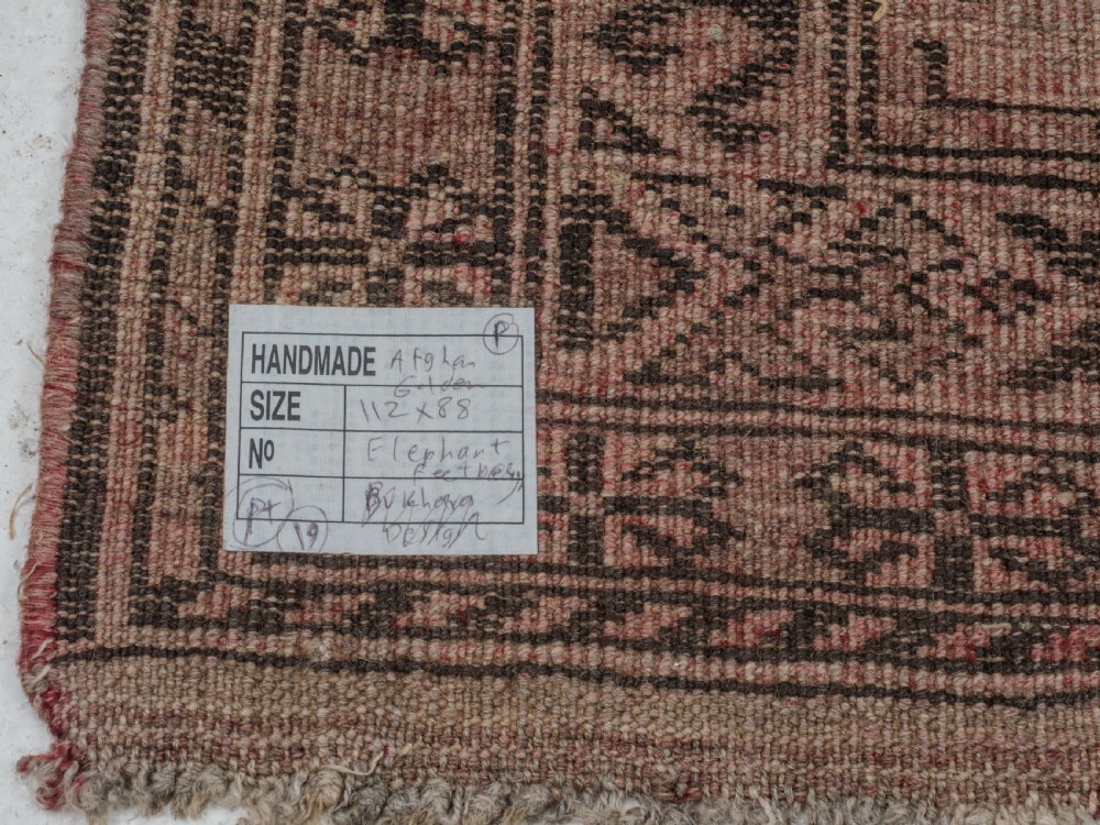 A small rectangular hand-knotted wool rug featuring two central octagonal gul medallions on a faded pink and beige ground with geometric borders. View X