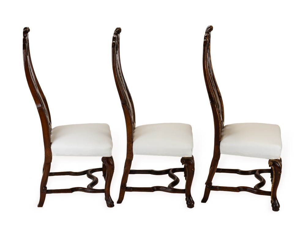 A set of six tall carved walnut dining chairs featuring gilt highlights, pierced splats, and white fabric drop-in seats. View IV