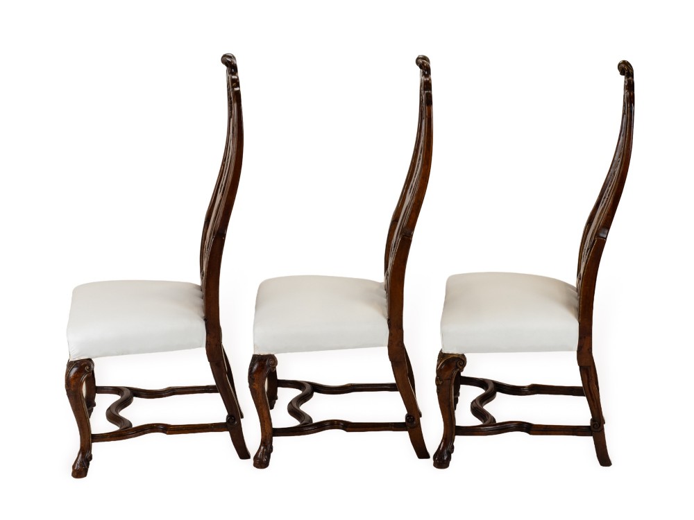 A set of six tall carved walnut dining chairs featuring gilt highlights, pierced splats, and white fabric drop-in seats. View V