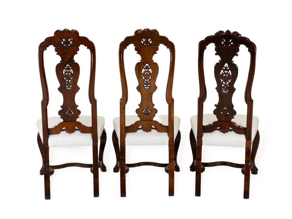 A set of six tall carved walnut dining chairs featuring gilt highlights, pierced splats, and white fabric drop-in seats. View VI