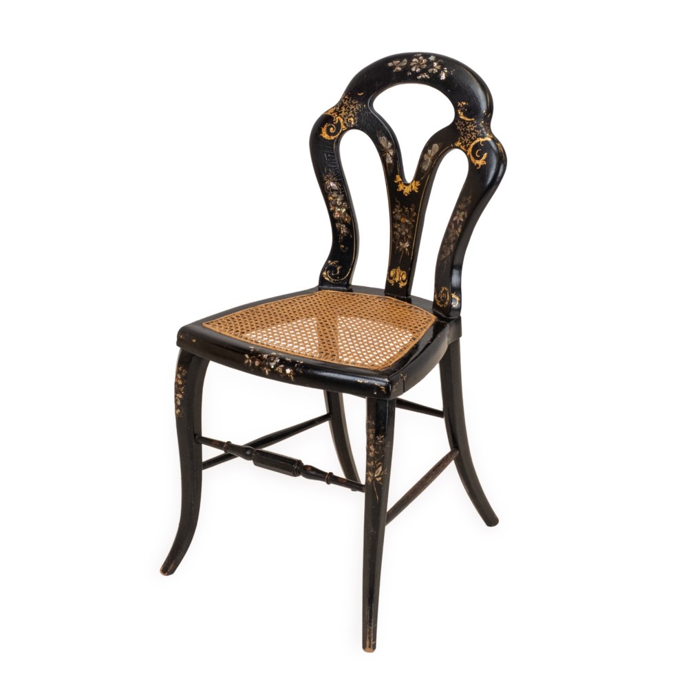 A black japanned papier-mache side chair with mother-of-pearl floral inlay, gold leaf flourishes, a openwork backrest, cabriole front legs, and a woven cane seat. View II