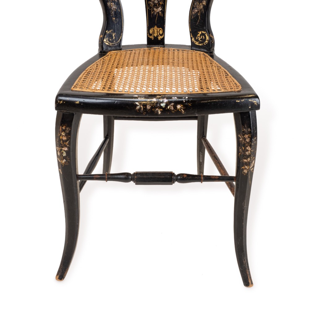A black japanned papier-mache side chair with mother-of-pearl floral inlay, gold leaf flourishes, a openwork backrest, cabriole front legs, and a woven cane seat. View V